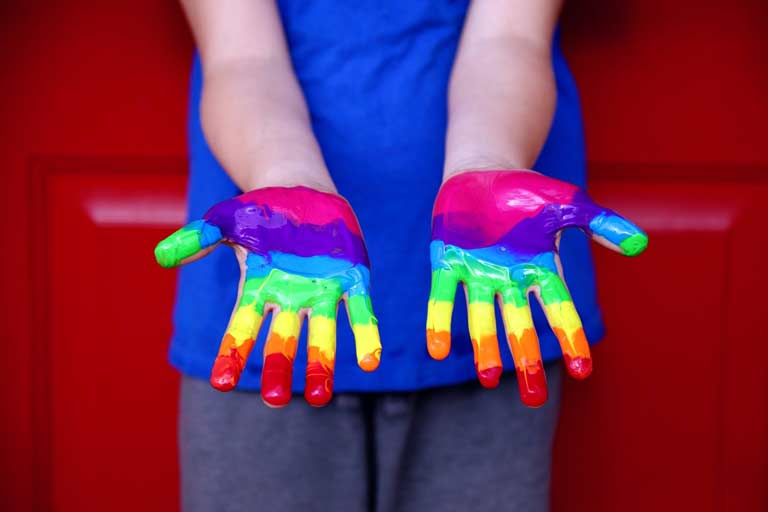 Two hands with a rainbow pattern painted on them.