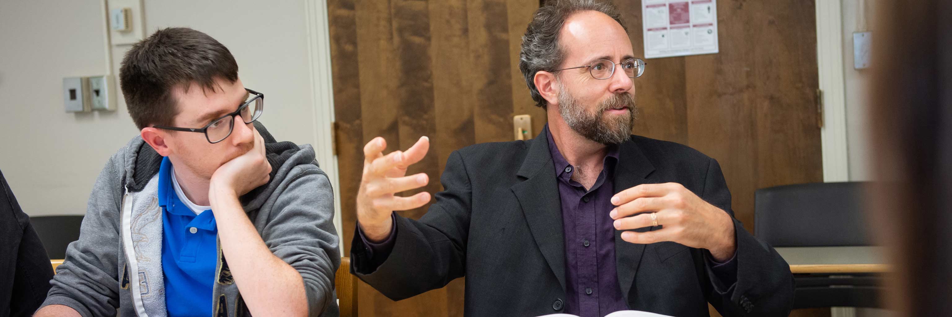 A professor speaks among a group of students.