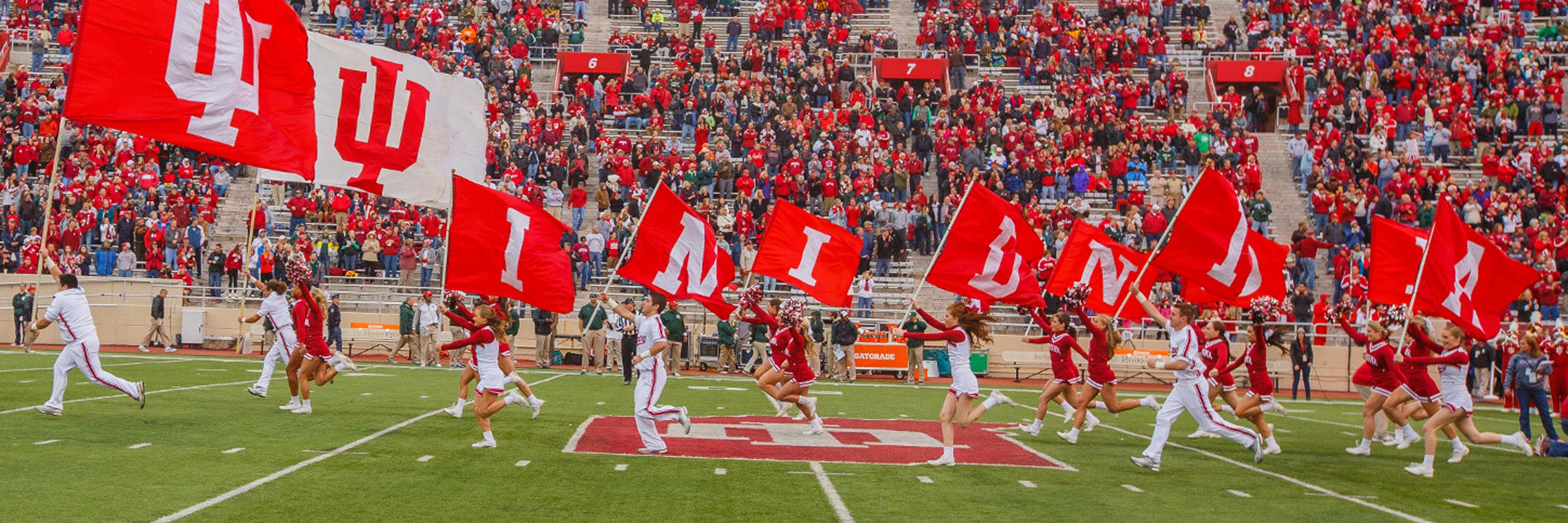 IU cheerleaders running across the football field.