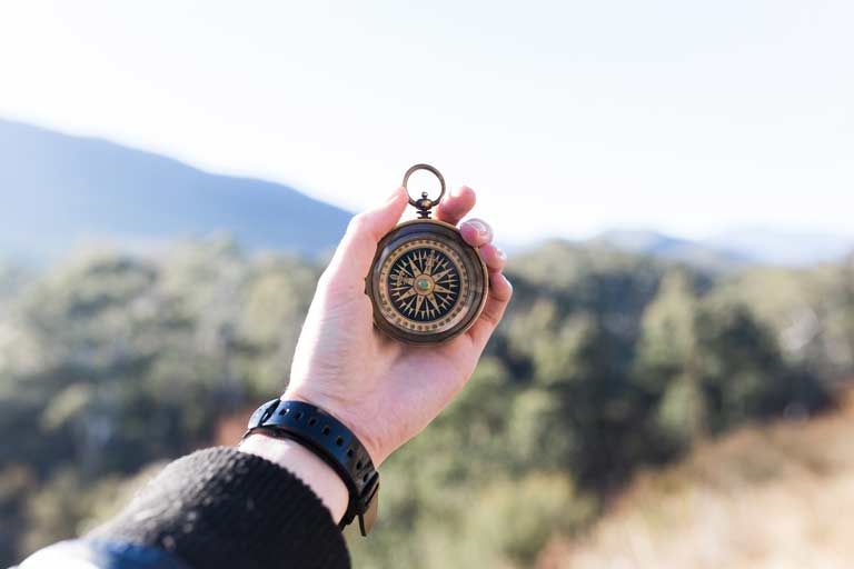 Hand holding up a compass.