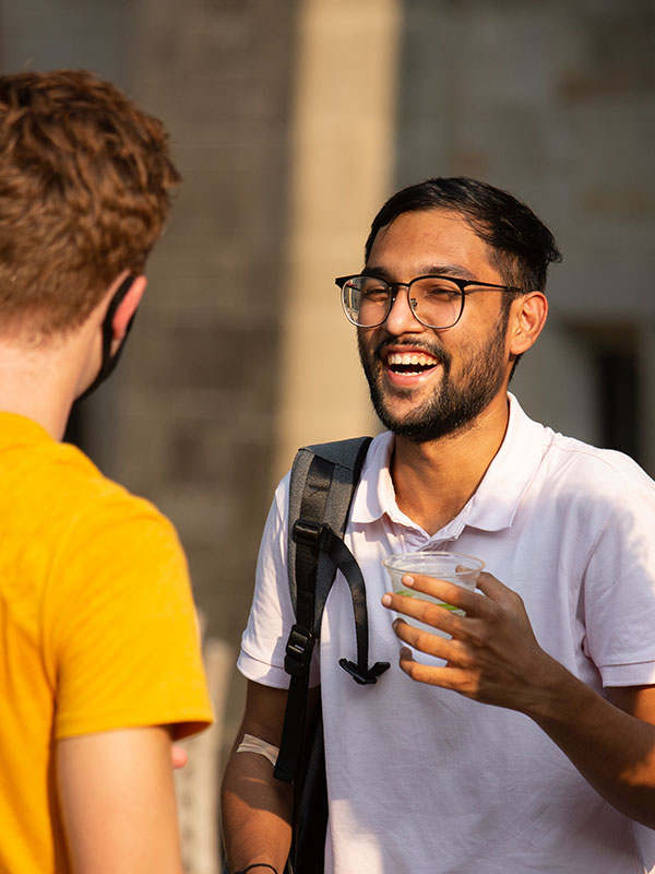 Two students talk outside on campus.